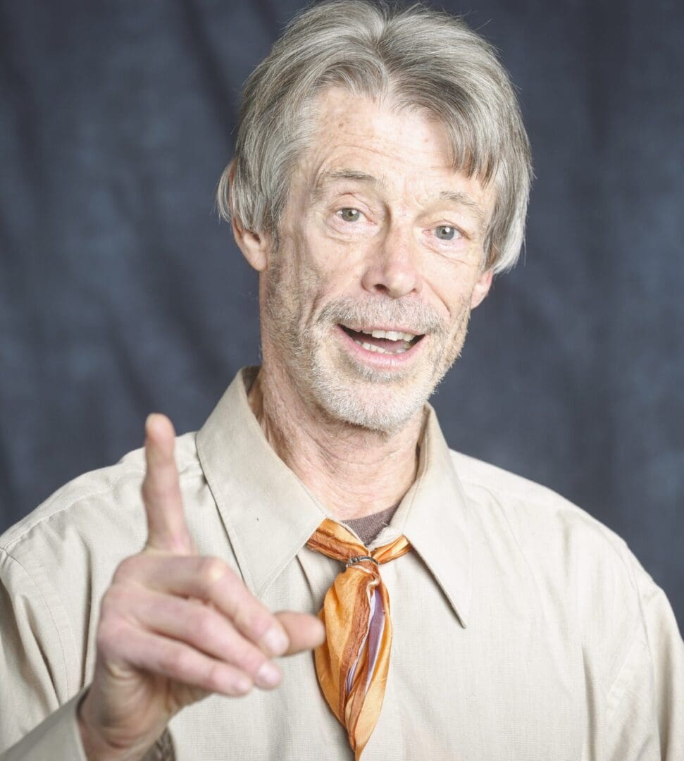 A man in tan shirt and tie making an ok sign.