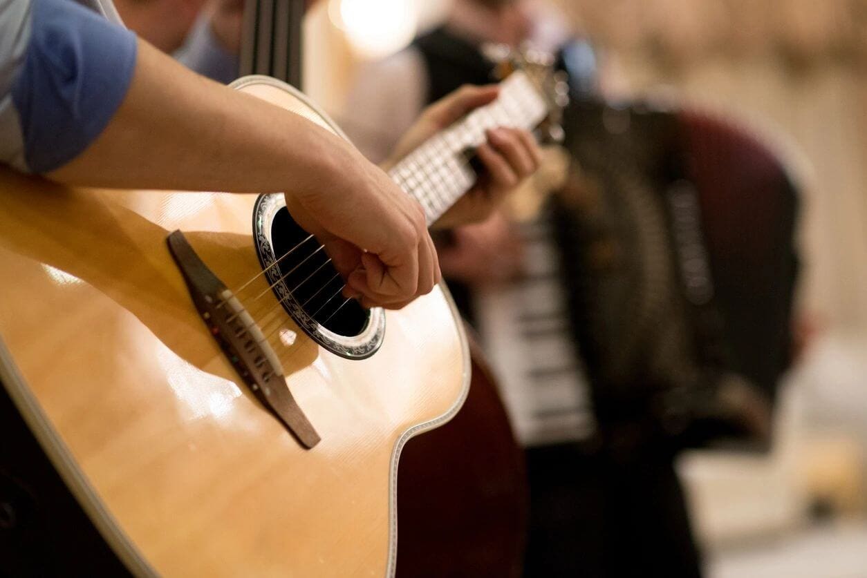 A person playing an instrument while others play the piano.