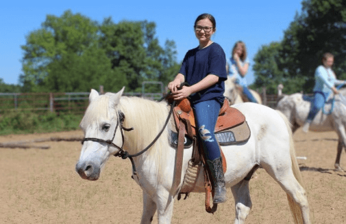 A woman is sitting on the back of a white horse.