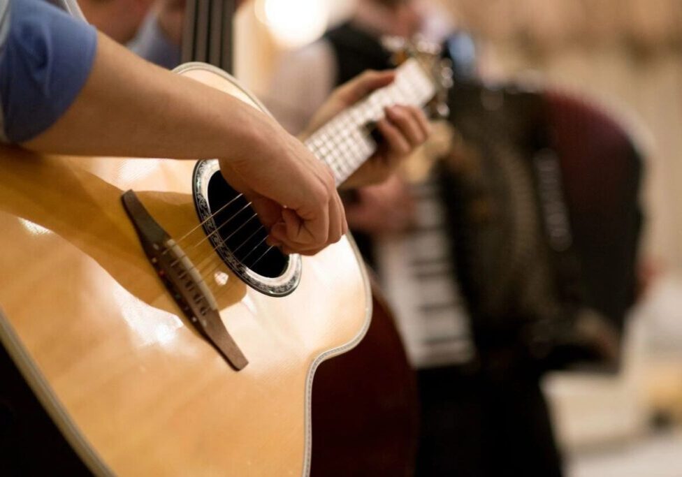 A person playing an instrument while others play the piano.